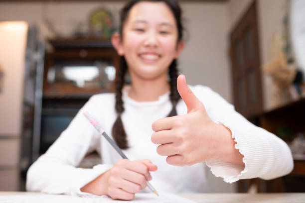 A child studying and giving a thumbs up