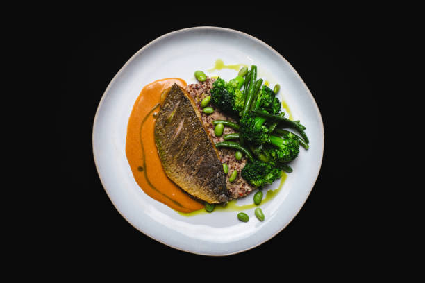 istock Golden fish fillet with vegetables on a black background. 2188034263