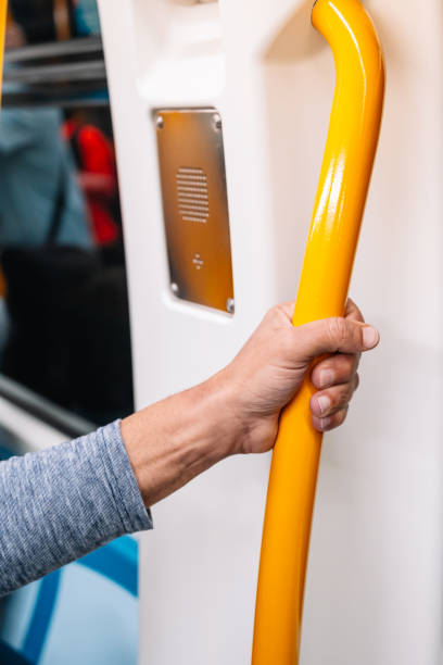 istock A person is holding a yellow pole on a train. The pole is attached to a yellow handle 2188037510