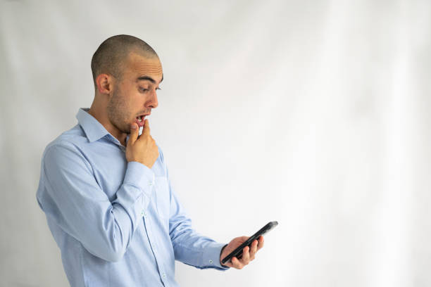 Impressed and shocked bald man looking at his cell phone screen