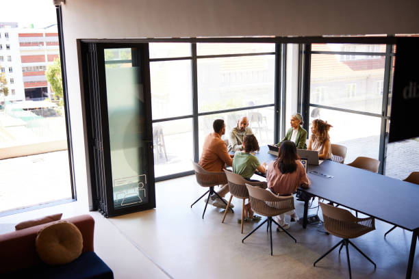 istock Six business people sitting at table having meeting in modern office, high angle 2188043431