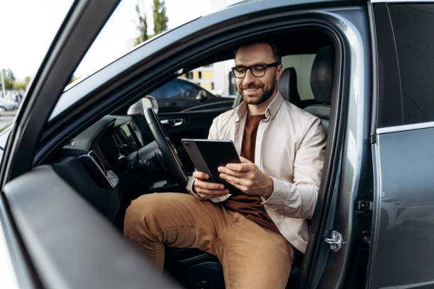 istock Happy, smiling Latin man holding digital tablet, using mobile app, sitting in modern new car 2188046594