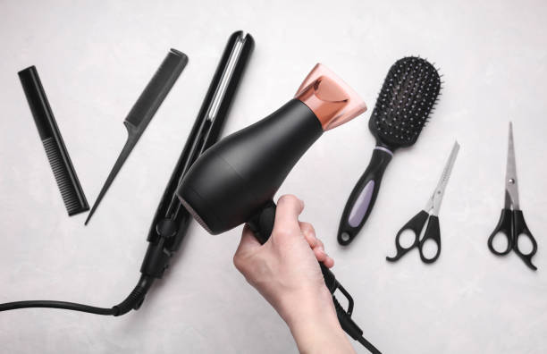 istock Hand holding hair dryer among hairdressing tools on grey background 2188047480