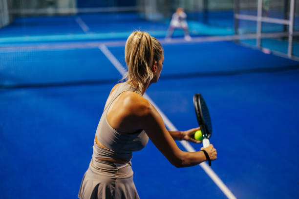 Blonde female padel player preparing to serve