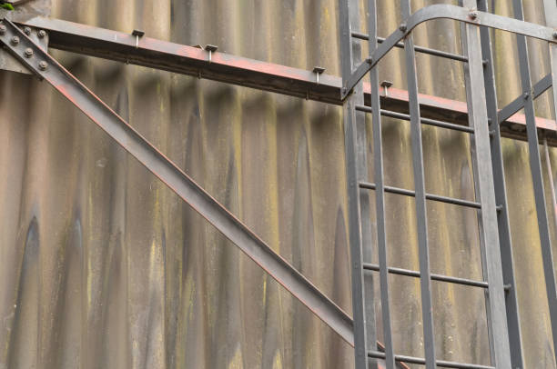 Close-up of a metal ladder and support beam attached to a corrugated metal wall, showing signs of weathering and rust