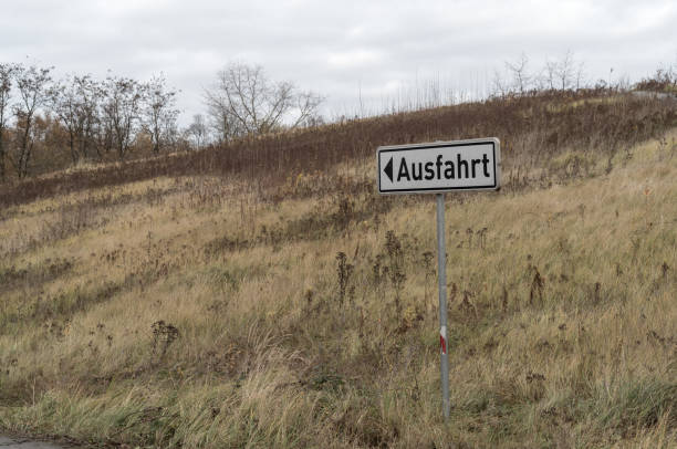 German exit sign pointing the way out of a dry grassy field in autumn