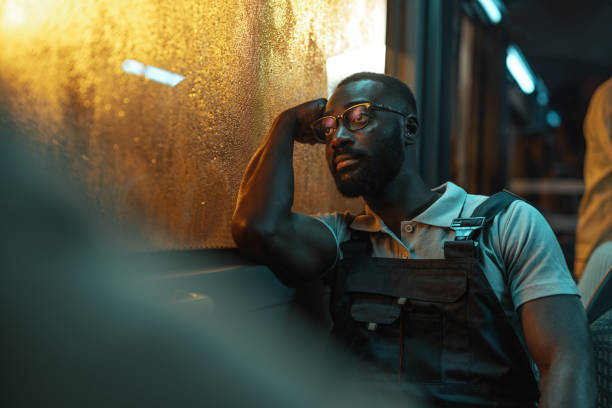 Man in overalls sitting on a bus at night