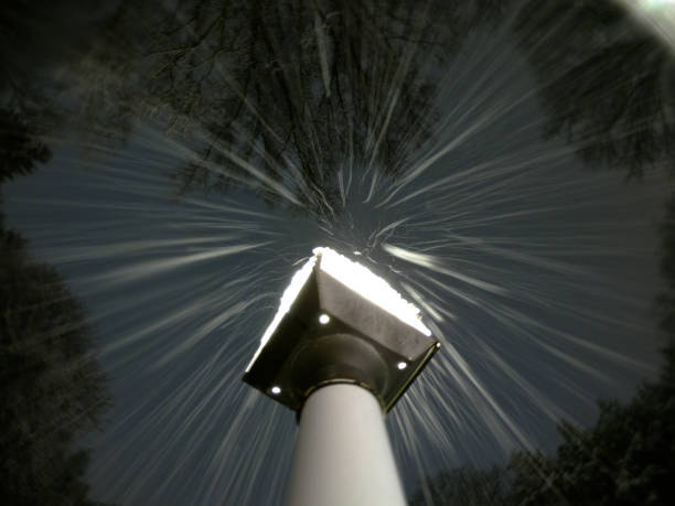 Long exposure of snow falling down upon a lampost at night