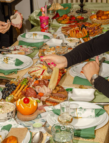 A woman's hand takes food from the dining table.
