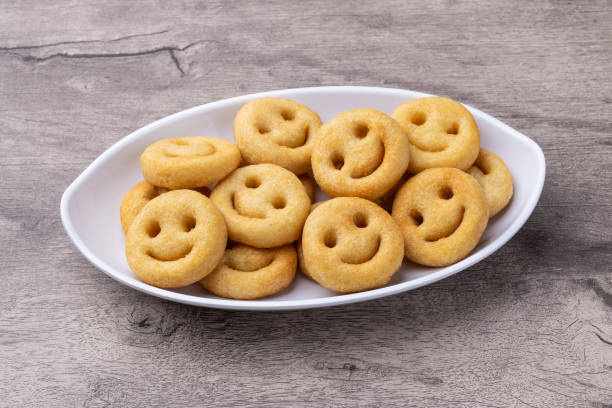 Smiley fried potatos in a plate over wooden table.