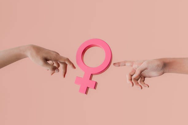 istock Two hands pointing at female gender symbol on peach background 2188066301