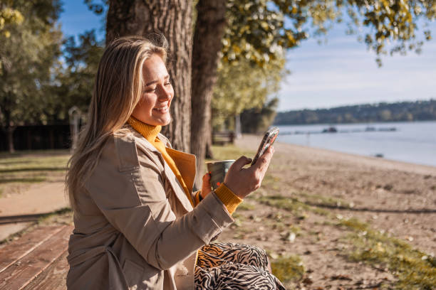 istock Woman Using Phone and Sipping Coffee on a Sunny Day 2188066618