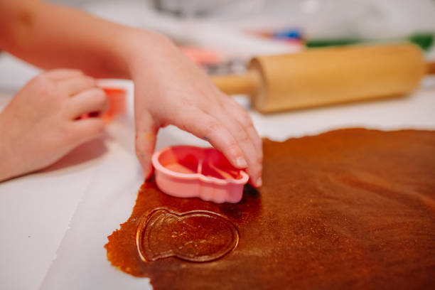 istock A childs hand pressing a pink cookie cutter into brown dough, with a rolling pin in the background, showing a festive baking moment. 2188068889