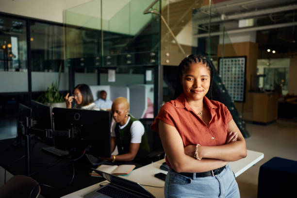 istock Young african american programmer smiling in modern office: sitting at desk and working on software development project 2188069554