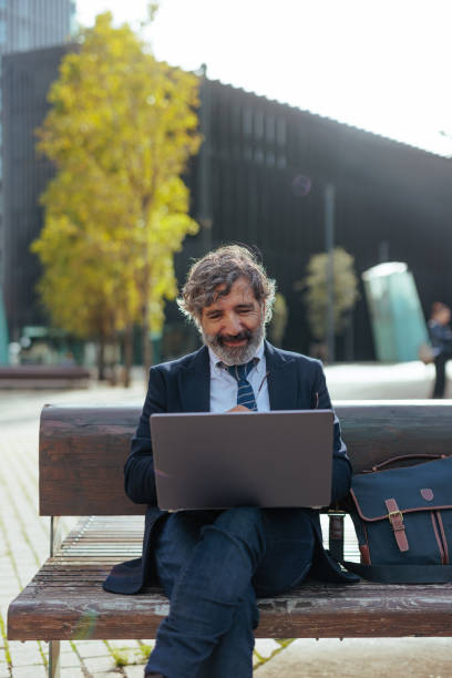 istock Businessman working on laptop outdoors in city park 2188070010