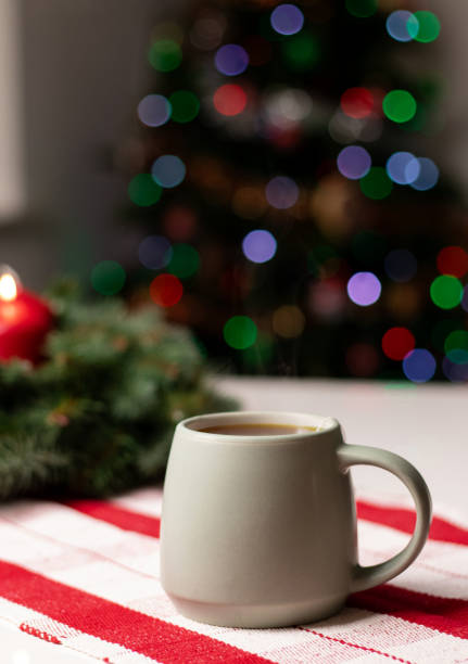 istock A cup with hot drink on white table with advent wreath and red candles, blurry background with Christmas tree lights 2188071051