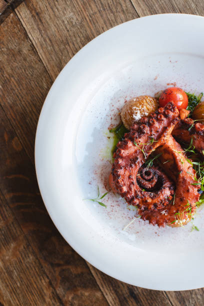 istock Octopus tentacles on a white plate in a restaurant interior. Wooden background. 2188071207