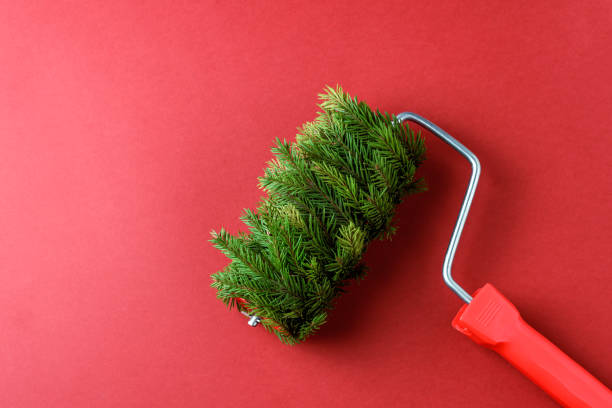 istock Paint roller covered with fir branches on a red background. A creative and unconventional concept symbolizing a mix of nature and creativity, perfect for festive themes 2188071623