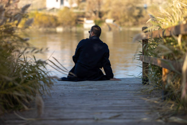 Alone man sitting on the edge of a pier