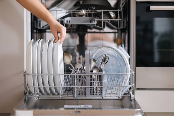 istock Front view from female hand removing clean plate from a loaded dishwasher. Background of modern kitchen 2188075668