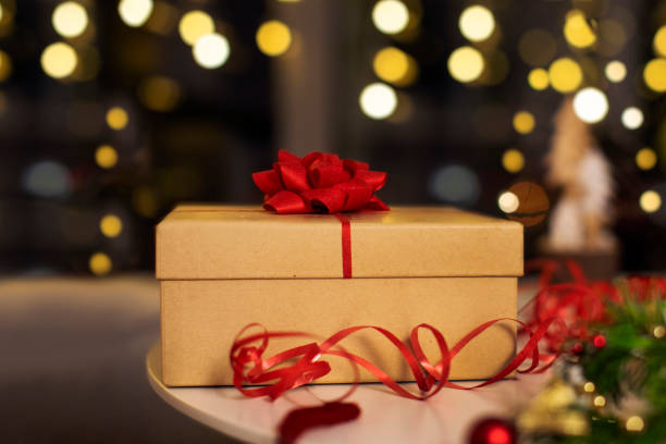 istock Beautiful wrapped present box decorated with red charming bow with bokeh of glowing lights on background. Christmas celebration atmosphere 2188077049
