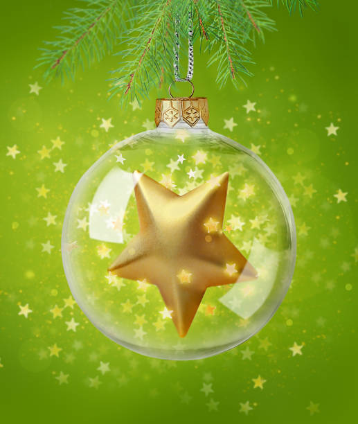 istock Transparent Christmas ball with sparkling star inside hanging on Christmas tree on green background surrounded by star shaped confetti 2188078403