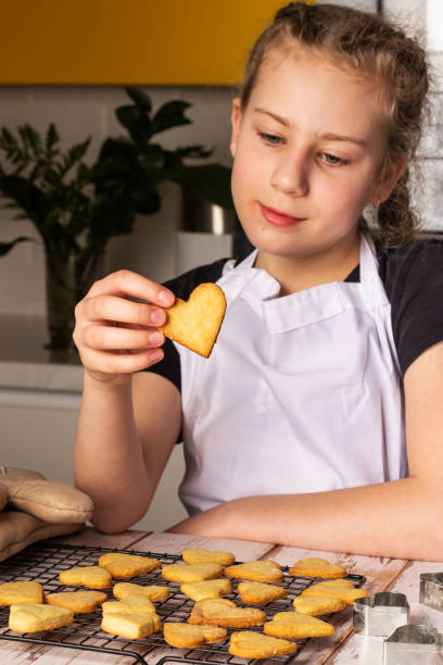 istock Young baker enjoys decorating heart-shaped cookies in a cozy kitchen 2188080988
