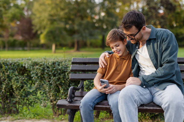 Digital Fun in the Park: Father and Son Enjoying Technology Together