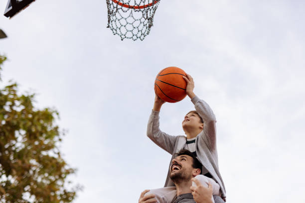 istock Father-Son Teamwork: Little Boy Aiming for the Hoop 2188083029