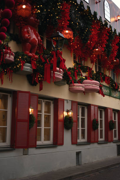 istock photo A richly decorated festive window display featuring decorative red ribbons, Christmas trees, lights, and giant macarons, creating a warm and inviting holiday atmosphere 2188084036