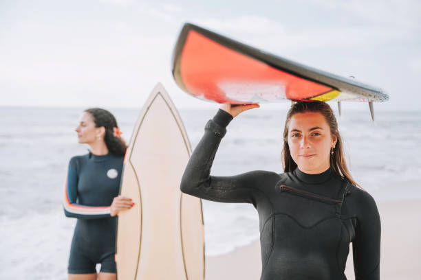 istock Two surfer friends holding surfboards over their heads 2188090694
