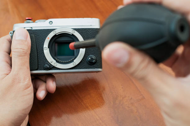 istock Cleaning the camera sensor with a blower on wooden table and 2188093189