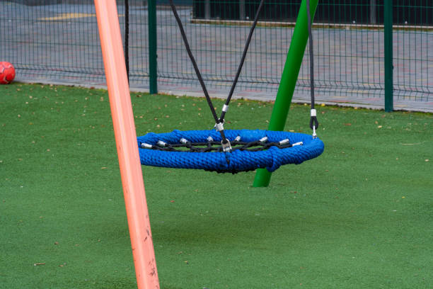 istock A colorful blue swing hangs in a lively public park, surrounded by soft grass, inviting children to experience joy and fun in their outdoor playtime 2188093372