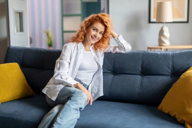 istock Happy European lady resting on comfortable sofa at home, looking and smiling at camera, enjoying leisure time at home 2188095984