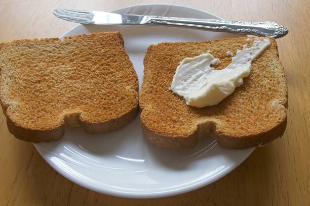 Sandwich spread and toasted bread in plate with table knife for spreading.