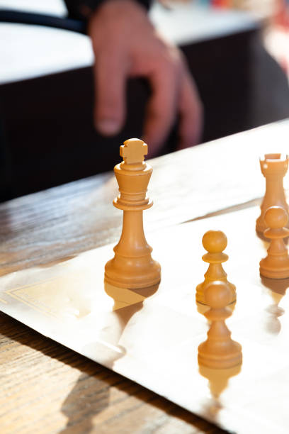 A person is actively engaged in a game of chess on a reflective mirror surface, demonstrating concentration and strategic thinking