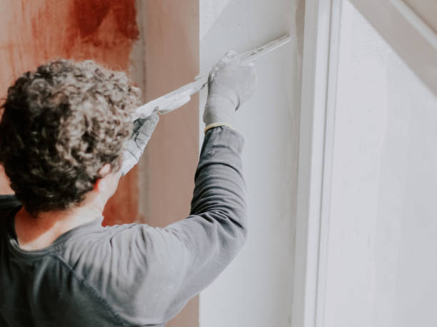 istock A Caucasian young man is putting putty on the wall. 2188101878