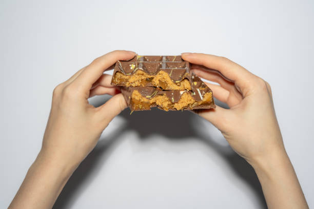 istock Trend Dubai chocolate with peanut butter, caramel and kadaif broken in woman's hands. Confectionery handmade sweets, chocolatier 2188110603