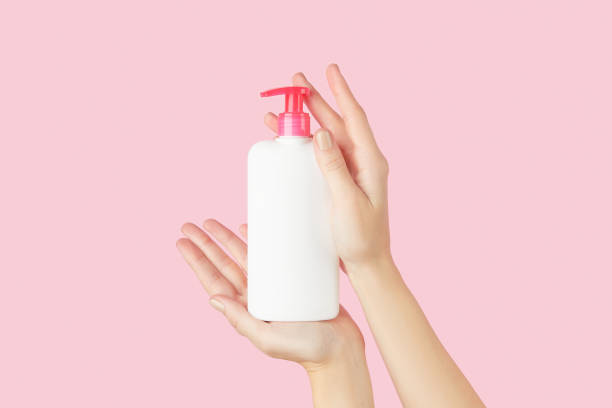 istock Womans hands holding white bottle on pastel pink background 2188112198