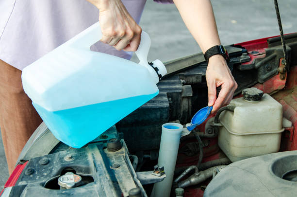istock Pouring liquid into car washer tank to clean the windshield. hands pour blue detergent from bottle 2188124469