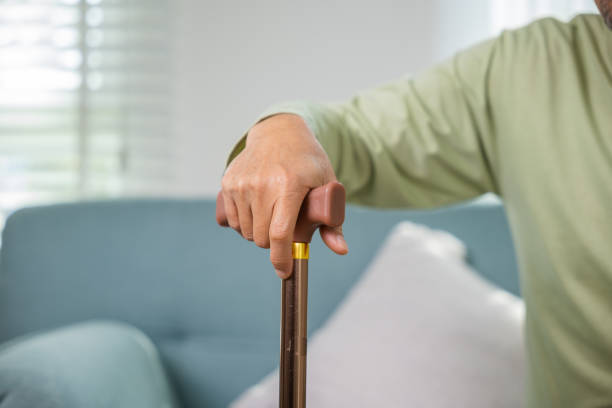 istock Asian Old man with eyeglasses typing to stand up from sofa with walking cane 2188128420