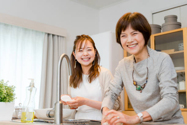 istock Two mothers and daughters looking at the camera in the kitchen at home 2188129511