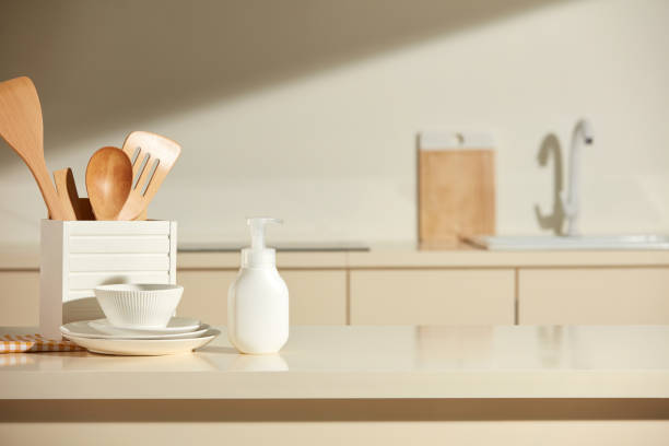 istock Kitchen concept photo for hygiene product advertisement. Bright beige kitchen counter as a blurred background behind the bokeh golden sunshine, white blank label bottle on kitchen island 2188130267