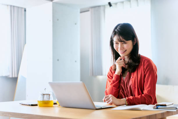 istock One woman who spreads studying tools on a table in a stylish room where bright light shines and looks at a laptop with a smile 2188132185