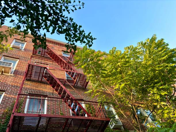 istock View of red brick apartment building, fire escape, trees, blue sky 2188133887