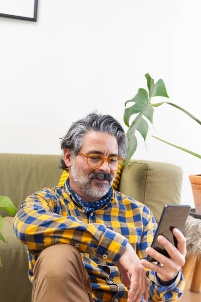 istock Smiling man using a smartphone sitting in his living room 2188134107