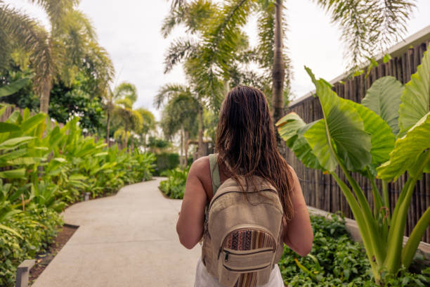 istock Woman with Backpack Walking on Tropical Pathway Surrounded by Lush Greenery 2188136100