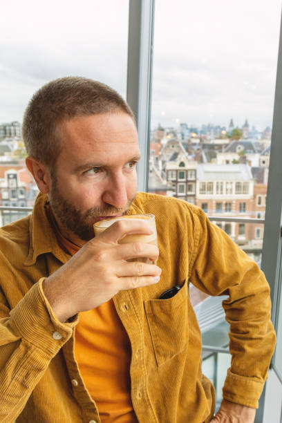 Man enjoying coffee at a cafe with a city view