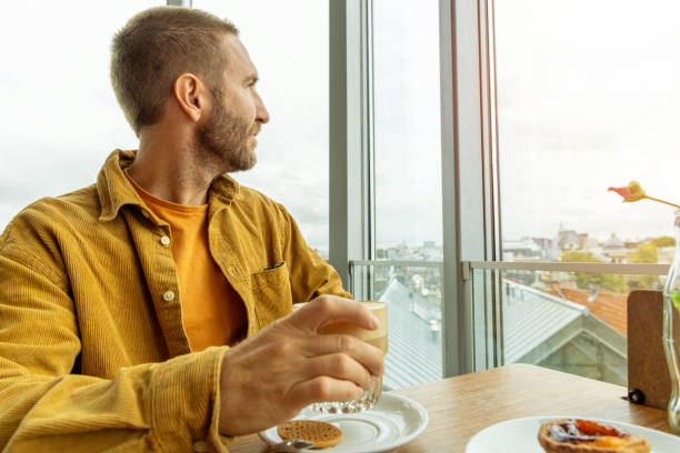 A man enjoys a chai latte in a cafe with Amsterdam city view