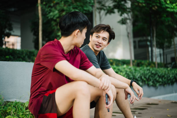 Two young Asian athletic friends take a break after exercising.